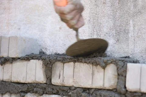Worker using trowel to put cement mortar on wall Stock Photos