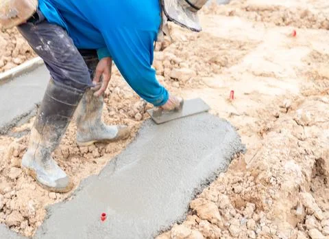 The worker is using a trowel to smooth the lean concrete. Stock Photos