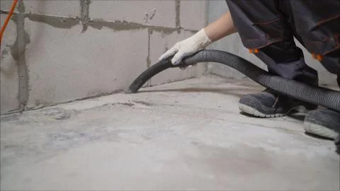 A worker using a vacuum cleaner removes construction debris. A worker is clea Stock Photos