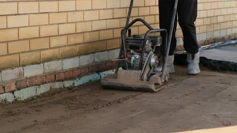 Worker using vibrating soil compactor for sand ramming. Stock Footage 287803428