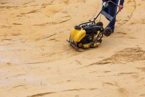 Worker using vibratory plate compactor for compaction sand during path Stock Photos