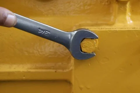 Worker using a wrench to fix a yellow metal structure. Stock Photos
