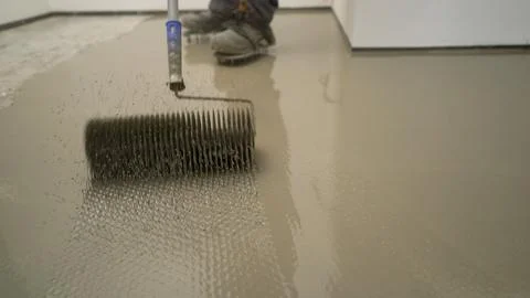 Worker ventilating self-leveling floor with spike roller Stock Photos