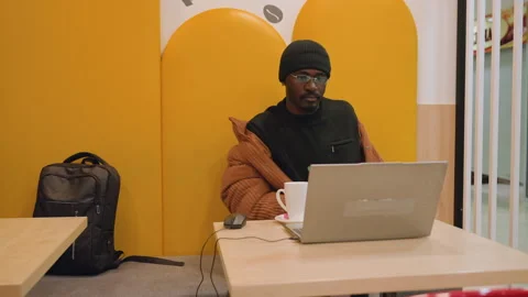 Worker in vibrant office changing outerwear during work session. Professional at Stock Footage 333189960