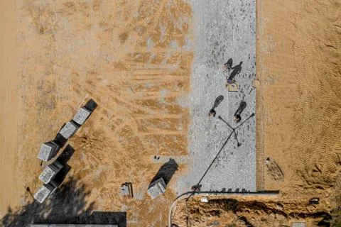 Worker with vibratory plate compactor compacting sand at road or sidewalk con Stock Photos