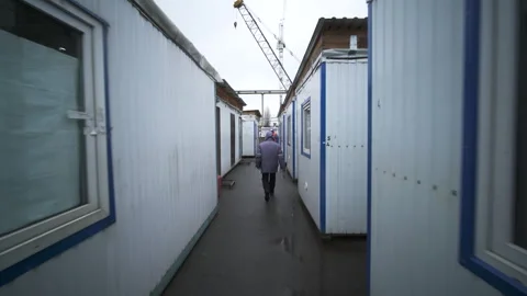 Worker walking past modular container units on site Stock Footage 345023608