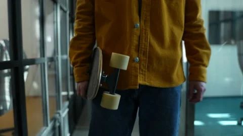 Worker walking with skateboard into office space Stock Footage 152346005