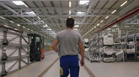 Worker walking though warehouse in factory with camera tracking Stock Footage 63007847