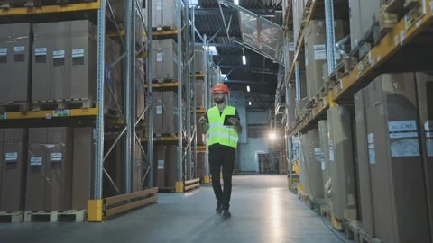 A worker walks along the rows of the warehouse. Industrial interior. Stock Footage 316908355