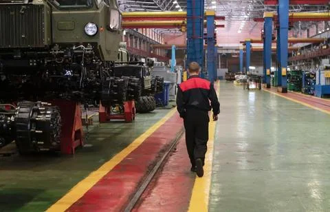 A worker walks down the assembly line of a military vehicle manufacturing fac Stock Photos