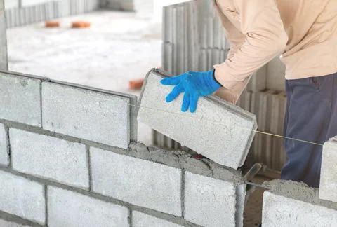 Worker ware blue gloves install concrete brick for wall. Foto stock
