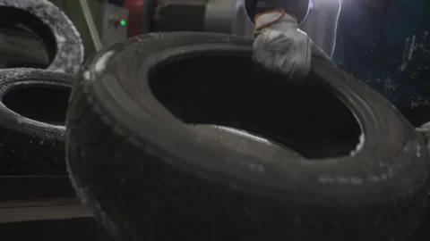 Worker in warm uniform stacks frozen tires in warehouse 動画素材 314640434