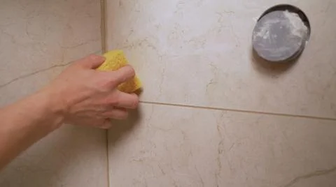 A worker washes the bathroom tiles with a sponge. A man in a yellow protectiv Stock Photos