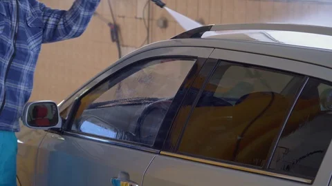 Worker washes a car with high-pressure water at a car wash Stock Footage 105967138