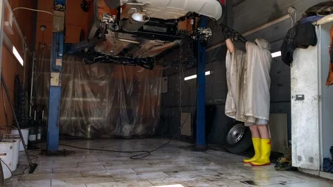 A worker washes the wheel arches and beams behind the car's shock absorbers. Stock Footage 255014372
