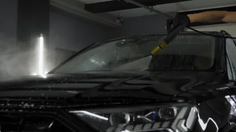 Worker washes the windshield with a high-pressure washer at a car wash. Video stock 247086534