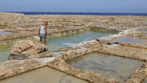 Worker washing hands inside salt pans in Malta Mediterranean sea Stock Footage 108390323