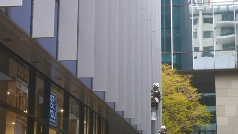 A worker washing windows on a building Stock Footage 92966997