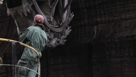 A worker is watching big machinery during lignite mining work in Ptolemaida Stock Footage 124773234
