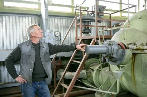 Worker watching correct work of an electric pump of a pumping station. Stock Photos