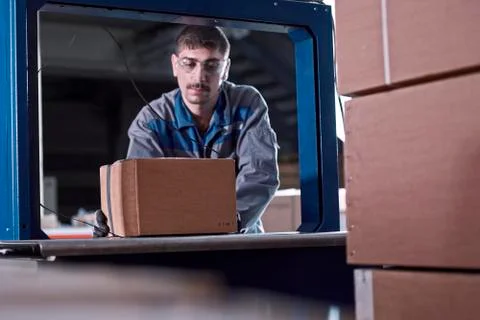 Worker watching machine closing packages 스톡 사진