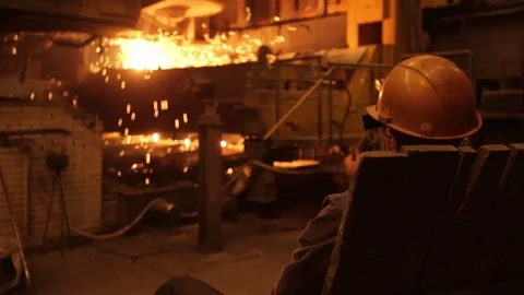 Worker watching the sparks bursting out of the iron melting furnace Stock Footage 72762831