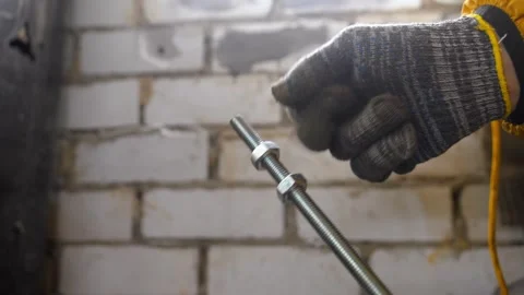 Worker wearing gloves twisting nut on threaded rod Stock Footage 327666006