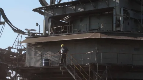 A worker wearing a helmet on top of a moving excavator in a coal mine in Gree Stock Footage 121013373