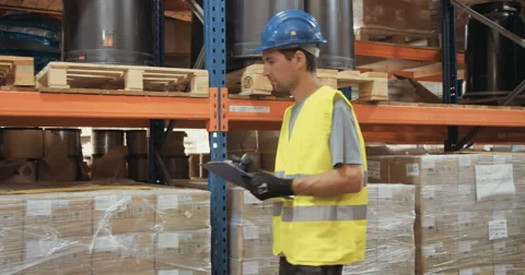 Worker wearing helmet walking in a warehouse working Stock Footage 65040984