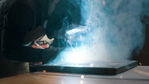 Worker wearing a mask and gloves soldering metal parts Stock Footage 142192252