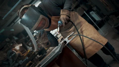 Worker wearing a mask and gloves soldering metal parts Stock Footage 142192753
