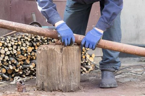 Worker wearing protective blue gloves stabilizes a rusty metal pipe on a wo.. Stock Photos