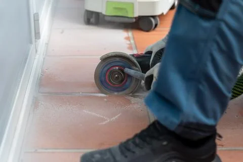 Worker wearing protective gloves cuts ceramic floor tiles with an angle grind Stock Photos