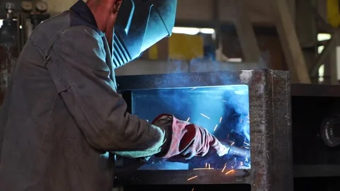 A worker wearing a protective mask welds metal in heavy manufacturing Stock Footage 243292835