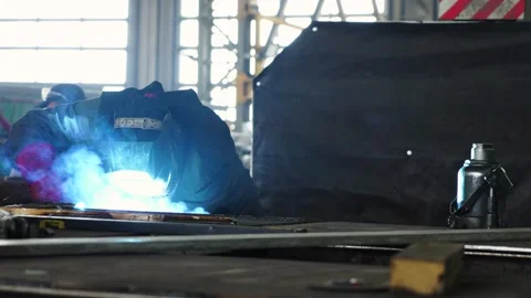 A worker wearing a protective mask welds metal in heavy manufacturing Stock Footage 243293120