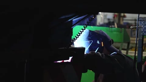 A worker wearing a protective mask welds metal in heavy manufacturing. Stock Footage 243661547