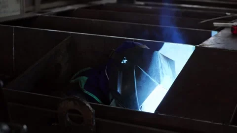 A worker wearing a protective mask welds metal in heavy manufacturing. Stock Footage 243661818