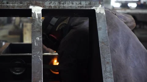 A worker wearing a protective mask welds metal in heavy manufacturing. Stock Footage 243848932