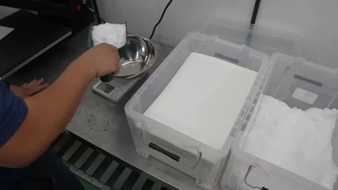 Worker weighs crushed ice on digital scale beside plastic container Stock Footage 339642847