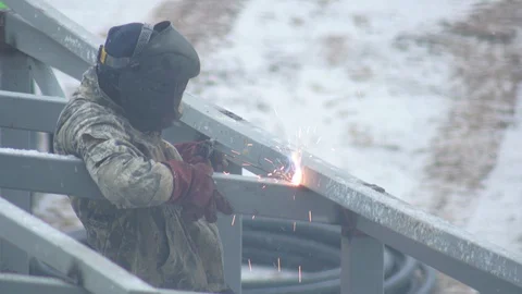 Worker welder in a protective helmet welds metal surfaces using an electrode Stock-Footage 129363029
