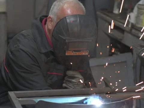 A Worker, welder in work clothes, construction gloves and a welding mask Stock Footage 255151252