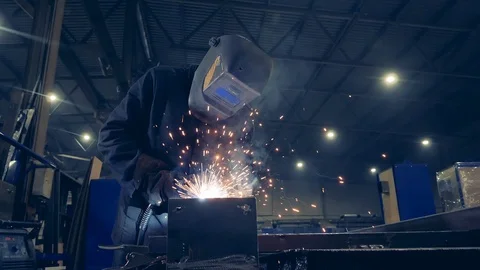 Worker in welder's helmet is welding metal. Slow motion. Stock Footage 123766784