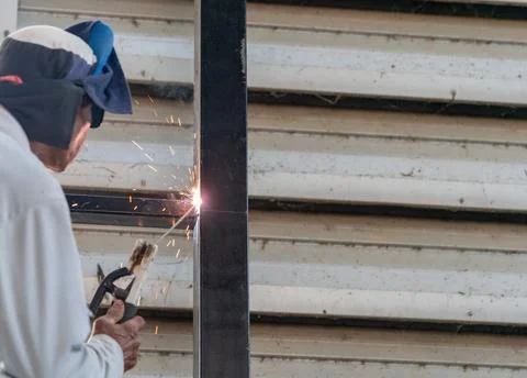 Worker welding black pole without personal protective equipment. Foto stock