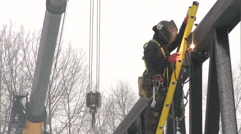 Worker welding bridge metal beam with a crane behind him Stock Footage 63919015