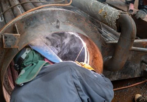Worker welding inside boiler. Stock Photos