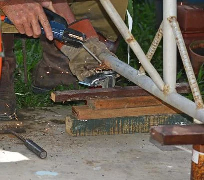 Worker with a welding machine fixing a caster wheels, sparks flying around Stock Photos