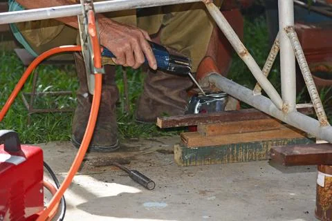 Worker with a welding machine fixing a caster wheels, sparks flying around Stock Photos