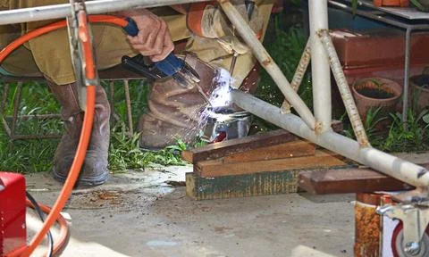 Worker with a welding machine fixing a caster wheels, sparks flying around Foto stock
