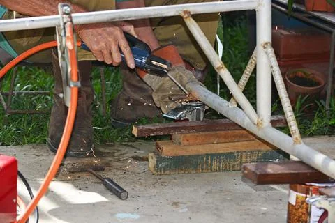 Worker with a welding machine fixing a caster wheels, sparks flying around Stock Photos