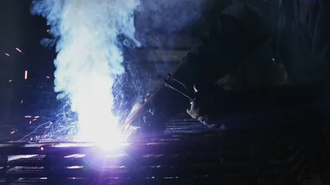 A worker with a welding machine performs welding work on metal Stock Footage 157156073